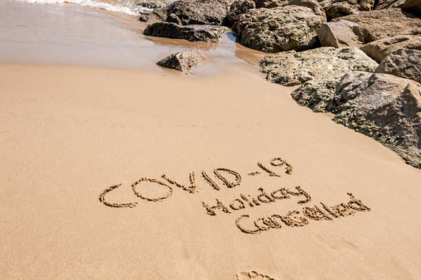 istock COVID-19 Holiday Cancelled written on a sandy beach 1221214833