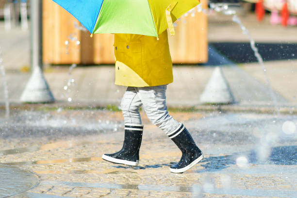 istock Girl in black rubber boots running through the puddles 1221215274