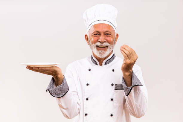 istock Senior chef with empty plate  showing delicious sign 1221215477
