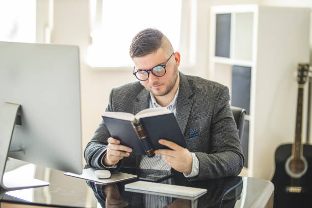 istock Businessman reading a book at home office 1221221905