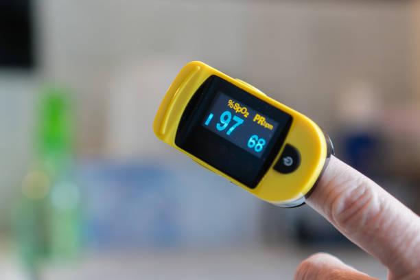 Pulse oximeter Close-up of hand with pulse oximeter attached to finger measuring blood oxygen and pulse rate pulse oxymeter stock pictures, royalty-free photos & images