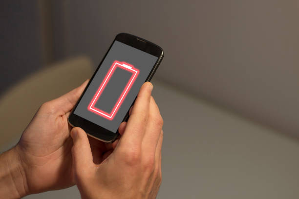 istock Hands holding mobile phone with low battery on the screen 1221222336
