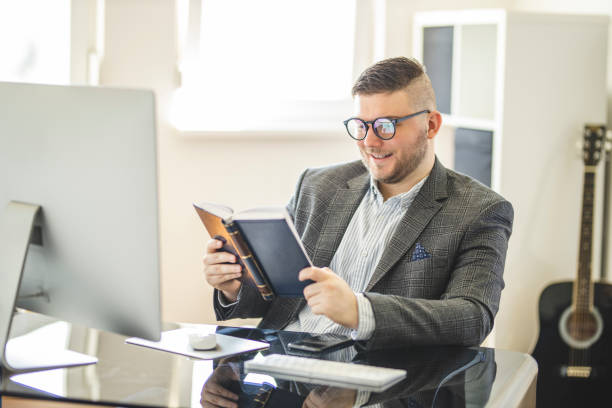 istock Businessman reading a book at home office 1221222497
