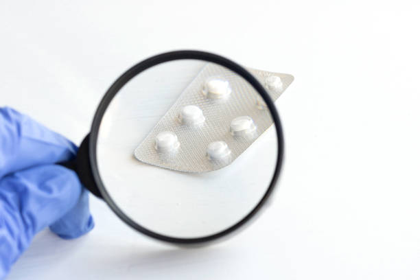 istock Hand holds a magnifying glass over pills on a white background. 1221222858