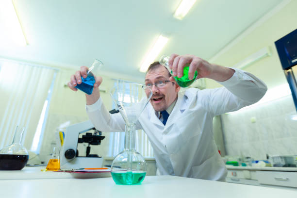 istock Chemist crazy. A mad scientist conducts experiments in a scientific laboratory. With a mad expression on his face, he mixes two liquids in a flask. COVID-19. COVID Coronavirus 1221223886
