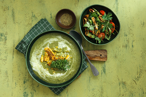 Vegetarian Spinach and Broccoli Soup with Corn, Garlic and Microgreen. Flat lay top-down composition on green background