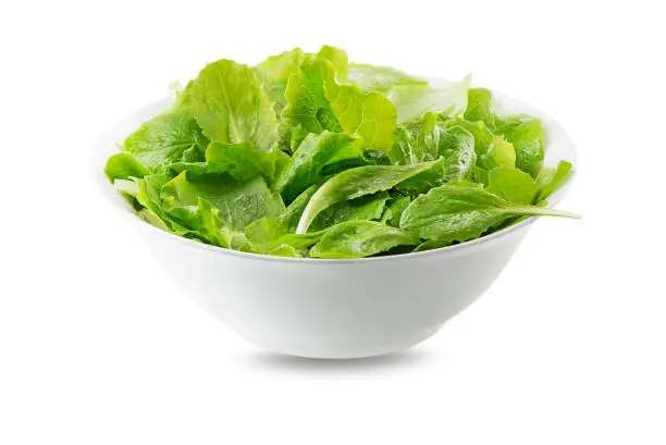 Green lettuce salad in bowl isolated on white. Freshly picked of young green leaves