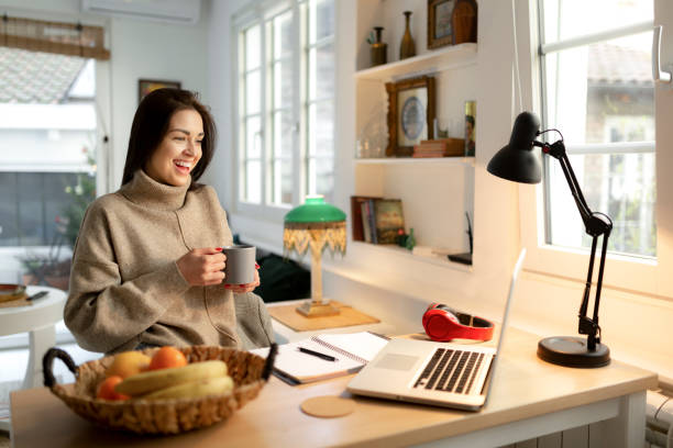 istock Smiling young woman working from home on a laptop 1221227172