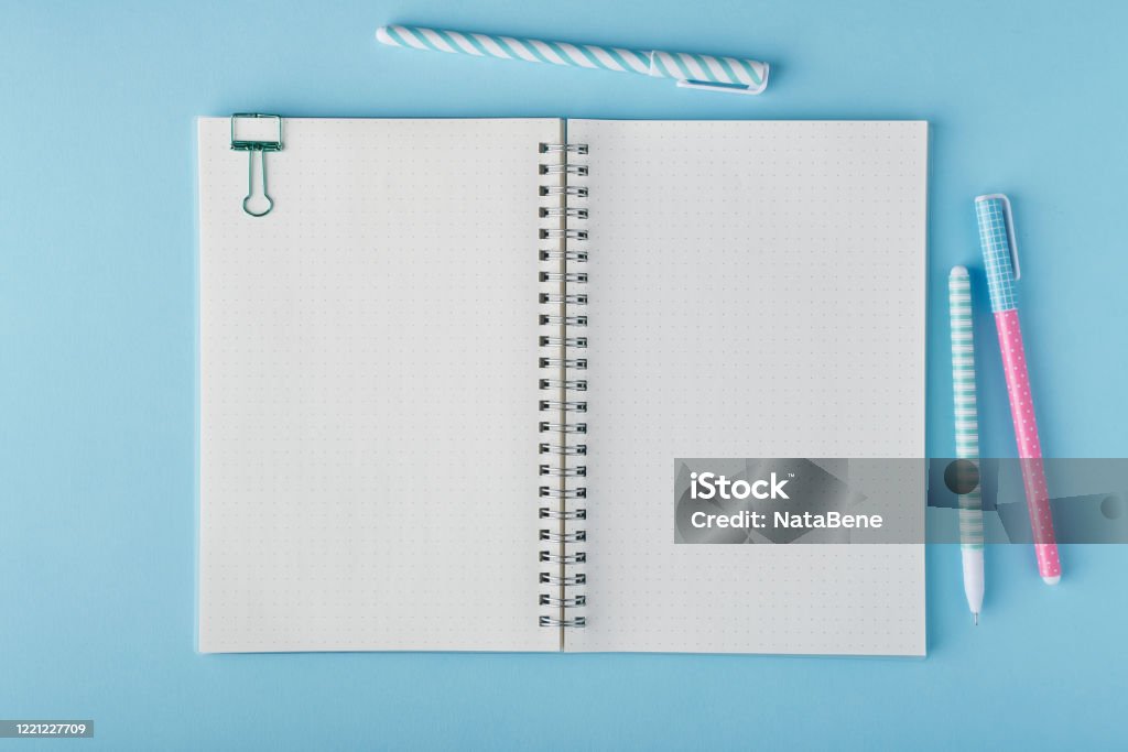 Blank notepad page in bullet journal on bright blue office desktop Blank notepad page in bullet journal on bright blue office desktop. Top view of modern table with notebook, stationery. Mock up, copy space, concept for diary, top view Bullet Journal Stock Photo
