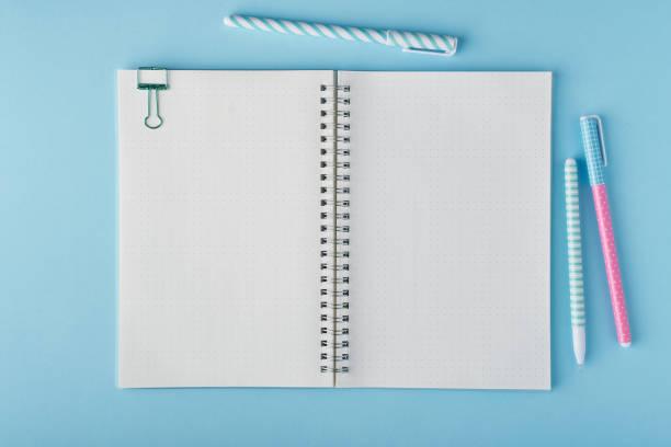 Blank notepad page in bullet journal on bright blue office desktop Blank notepad page in bullet journal on bright blue office desktop. Top view of modern table with notebook, stationery. Mock up, copy space, concept for diary, top view bullet journal photos stock pictures, royalty-free photos & images