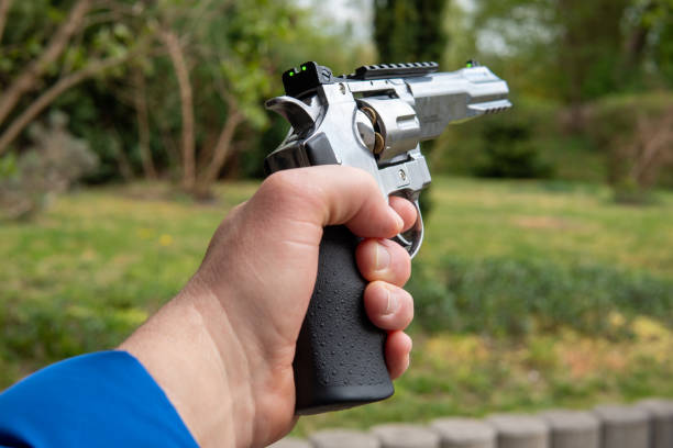 istock one left hand holds a big silver revolver in the air 1221235098