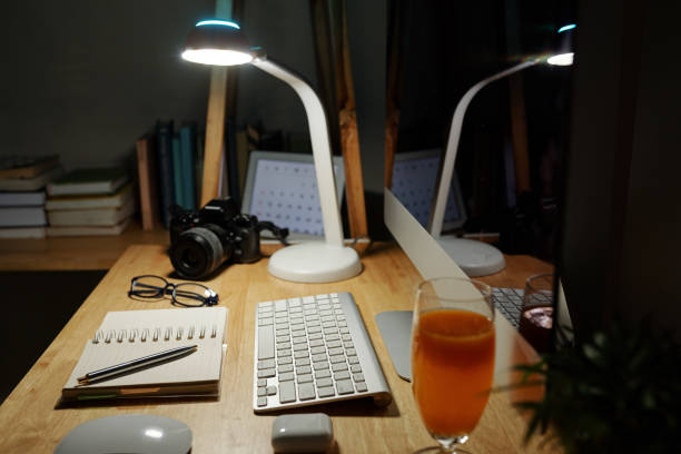 Wooden desk with computer, planner and lamp. Workplace of person staying home during quarantine