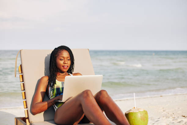 istock Woman resting on chaise-lounge with laptop 1221235594
