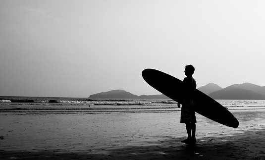 Silhouette of a surfer watching the sea.
