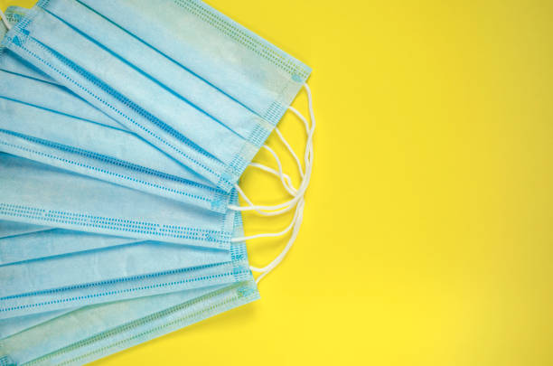 Medical mask on the yellow background top view. Surgical masks flat lay with copy space. Coronavirus protection. Stop Covid-19. Hygiene and healthcare theme. Global quarantine and social distancing. máscara médica en la vista superior de fondo amarillo. las máscaras quirúrgicas planas estaban con espacio de copia. protección del coronavirus. detenga covid-19. tema de higiene y atención médica. cuarentena global y distanciamiento social.