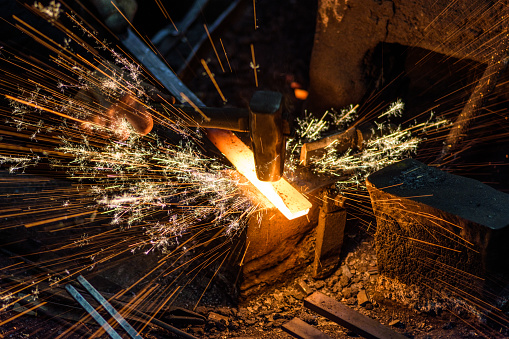 Herrero manualmente forjar el metal fundido en el yunque con fuegos artificiales chispa photo