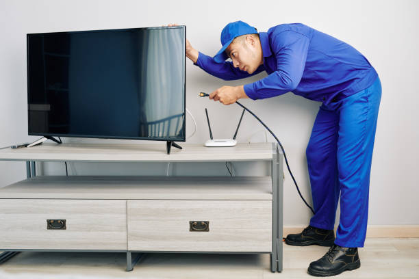 Repairman installing tv set Serious young Vietnamese repairman installing tv set in apartment of customer cable tv stock pictures, royalty-free photos & images