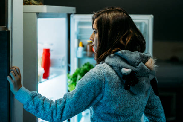 istock Young girl at night in front of a refrigerator 1221240889