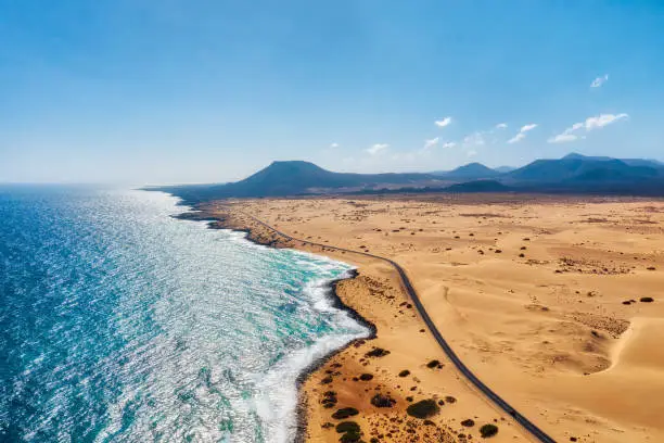 Rocky coastline and highway with golden sand and blue water, post processed in HDR