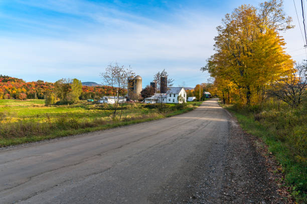 Rural landscape with a farm along an unpaved back road on a clear autumn day. Stunning autumn colours. Contryside of Vermont, USA.