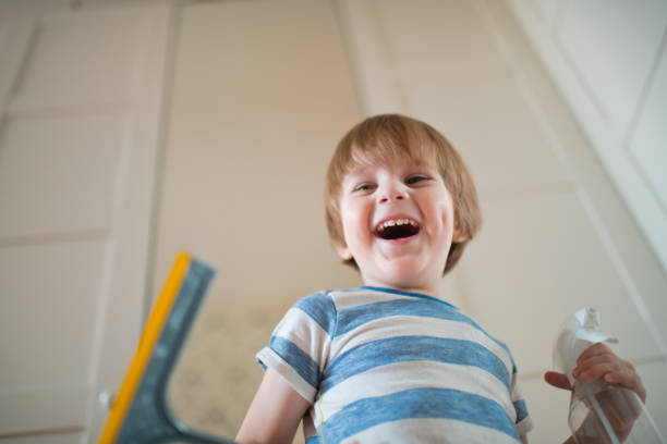 Cute child washing mirror indoors