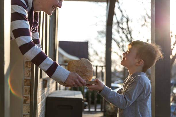 joven niño pelirrojo lindo trayendo pan casero a la puerta del vecino - isolated despair hope assistance fotografías e imágenes de stock