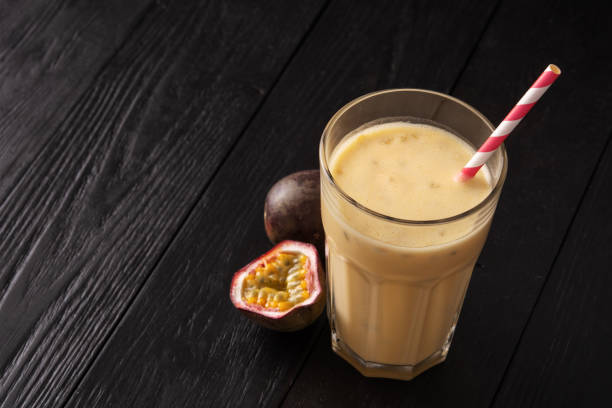 istock Fruit protein shake on a black wooden background. Fresh milkshake with passion fruit. A glass of protein shake. 1221246486