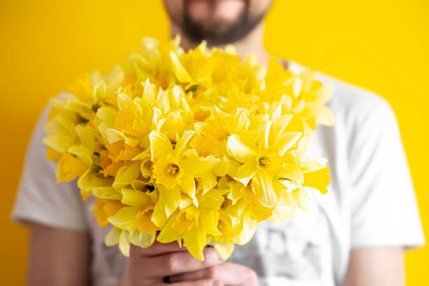 hipster man on a yellow background in a shirt and a bouquet of flowers. - daffodil flower yellow vase imagens e fotografias de stock