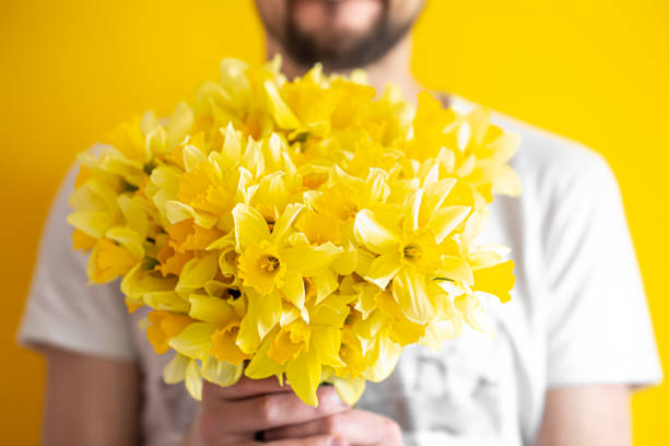 хипстер на желтом фоне в рубашке и букете цветов. - daffodil flower yellow vase стоковые фото и изображения