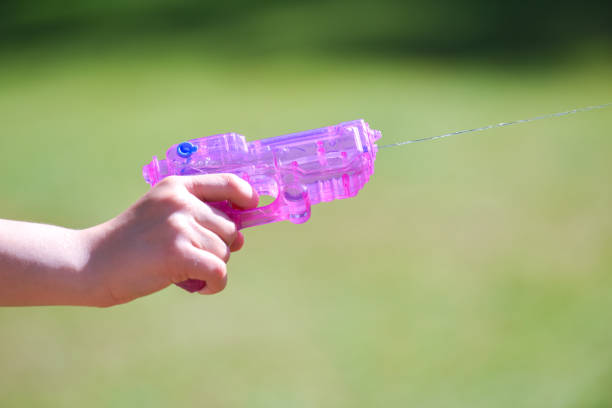pistola de agua rosa disparando agua de cerca en un jardín - toy gun fotografías e imágenes de stock