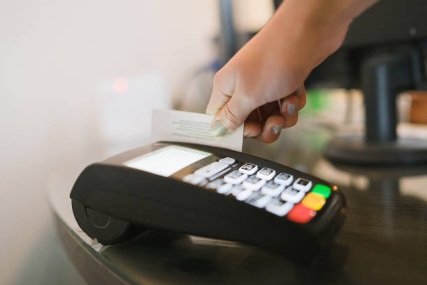 Close up side view on caucasian female hand holding debit or credit payment card using to pay the bill at the store on the terminal payment machine Close up side view on caucasian female hand holding debit or credit payment card using to pay the bill at the store on the terminal payment machine smart card stock pictures, royalty-free photos & images