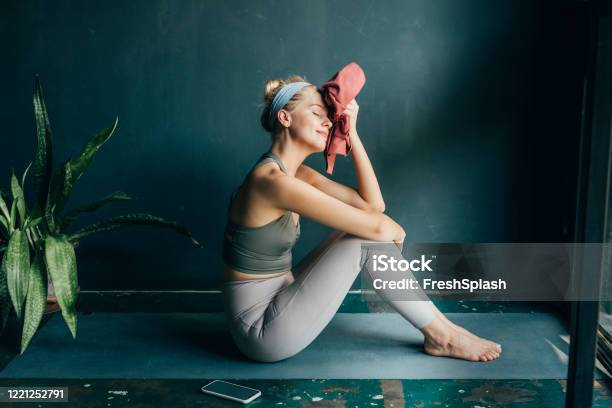 Tired But Happy Fit Blonde Woman Wiping Her Face With A Towel After A Home Workout Stock Photo - Download Image Now