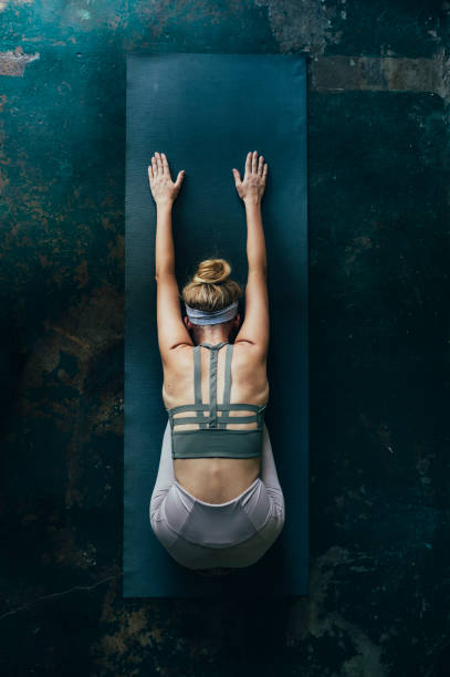 rituali di cura di sé: donna bionda che fa yoga a casa, una vista aerea - stretching back rear view women foto e immagini stock