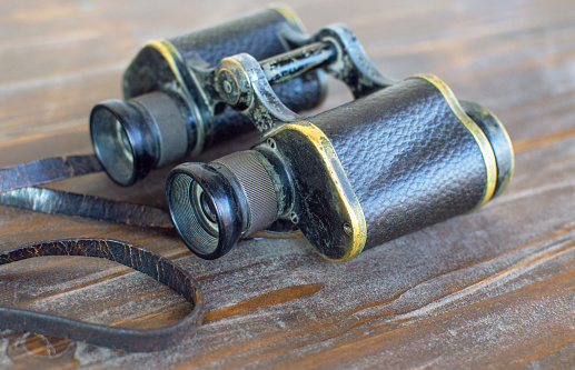 Vintage military binoculars on old wooden table