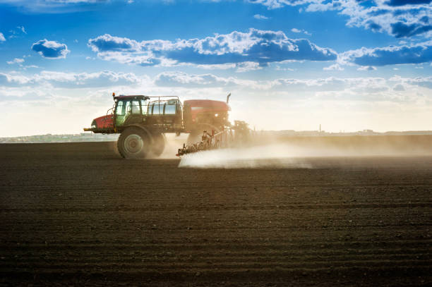 istock Big red spraying machine working on the plowed field 1221254913