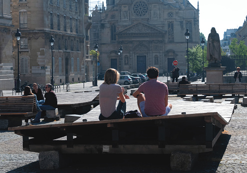 Paris, France, April 26th 2020. People of the neighborhood on benches on the Pantheon place, the church Saint-Etienne-du-Mont and the college Henry IV during the confinement in France.