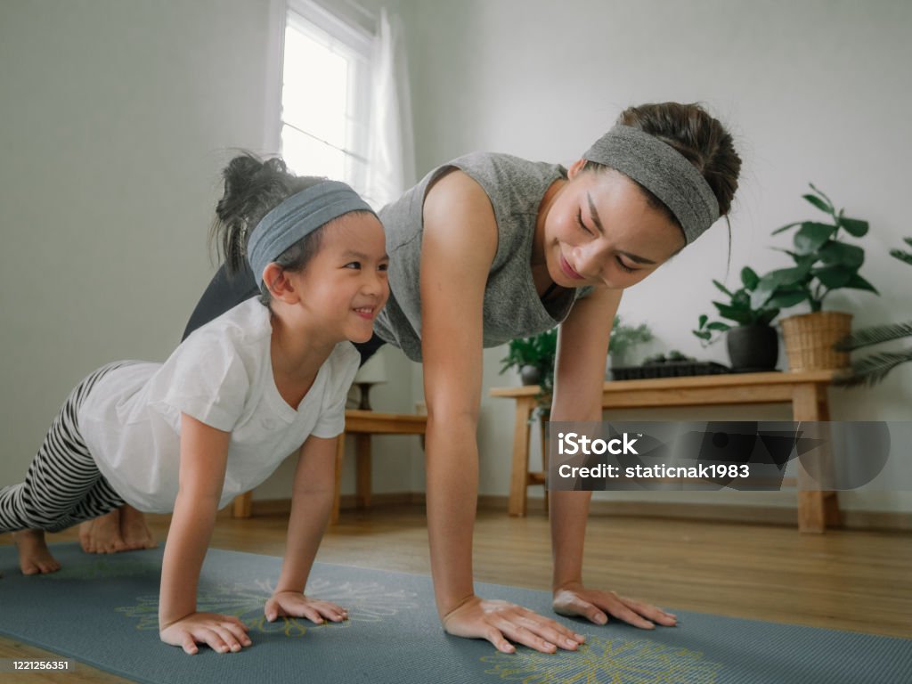 Mother and daughter doing yoga Sport young asian woman work out with little girl at home Exercising Stock Photo