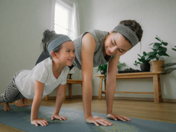 mother and daughter doing yoga - healthy lifestyle dieting indoors lifestyles imagens e fotografias de stock