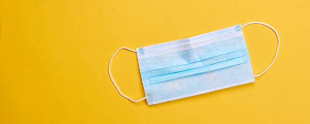 istock surgical face protective mask over bright yellow background. epidemic symbol concept. space for text. 1221257017
