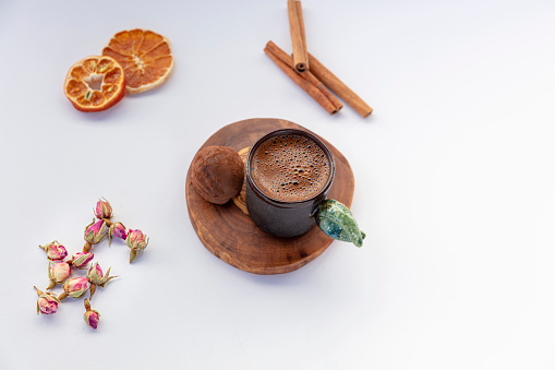 cup of coffee with cinnamon,dry fruit, dry rose and delicious cake on white background