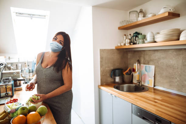 pregnant woman cooking with face mask during the quarantine - mother emotional stress exhaustion cooking imagens e fotografias de stock