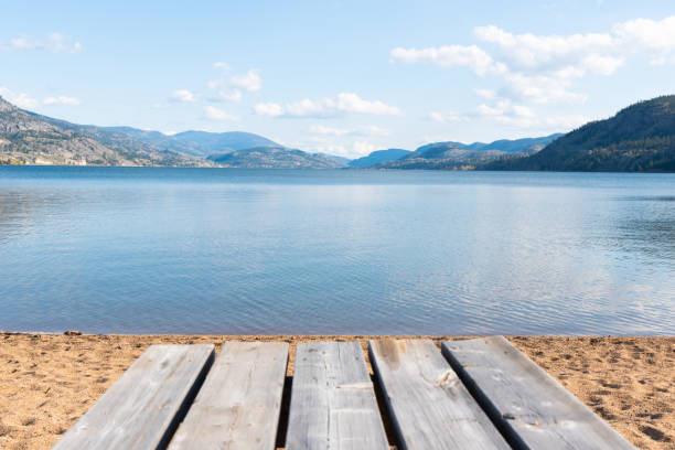 Picnic table in foreground with view of Skaha Lake on sunny afternoon in Penticton, BC, Canada