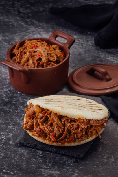 istock Arepa stuffed with shredded meat on a dark background. (Arepa con carne mechada) 1221261897