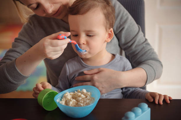istock Mother feeding toddler boy at dining table 1221262168