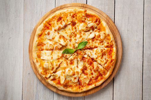 Tasty hawaiian pizza with chicken and pineapple on wooden cutting board. Top view with copyspace