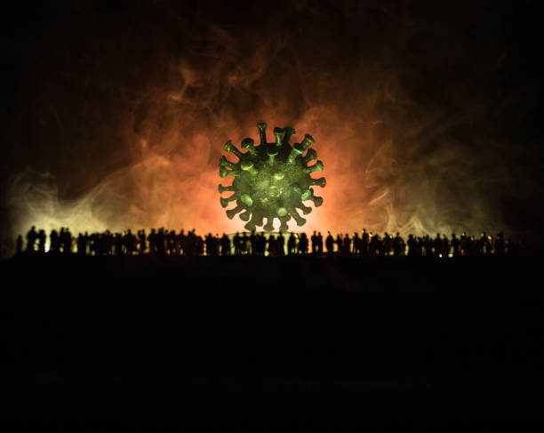 istock Coronavirus 2019-nCov novel coronavirus concept. Crowd looking on big Corona virus model at night with fog and backlight. Creative artwork decoration. Selective focus. 1221263002
