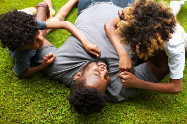 istock African-American father playing with two sons laying on grass 1221265178