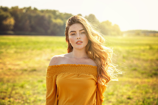 Nature, summer holidays, vacation. Happy young woman in yellow dress enjoying sun on countryside.