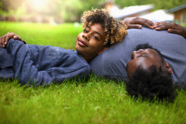 istock African-American son lays on father chest on grass at backyard 1221266172