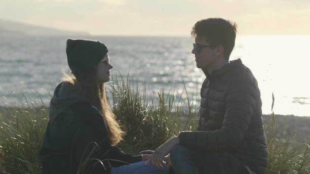 istock Two friends have fun while sitting at the beach 1221267361